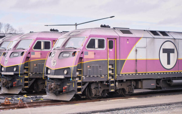 Photo of MBTA Commuter Rail purple train cars parked at lot. The train cars shown in the photo run on dirty fossil fuels that pollute the communities along the route of these trains.
