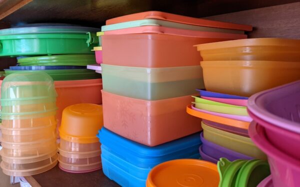 A pile of colorful plastic tupperware containers on a shelf.
