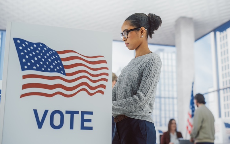 Young Stylish African American Female Casting Her Vote at a Polling Station and Putting Her Ballot into a Sealed Box. American People on Elections Day in the United States of America