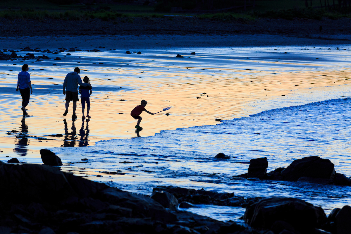 A couple and their kids walk on the sand after sunset at Seapoint Beach in Kittery, Maine.