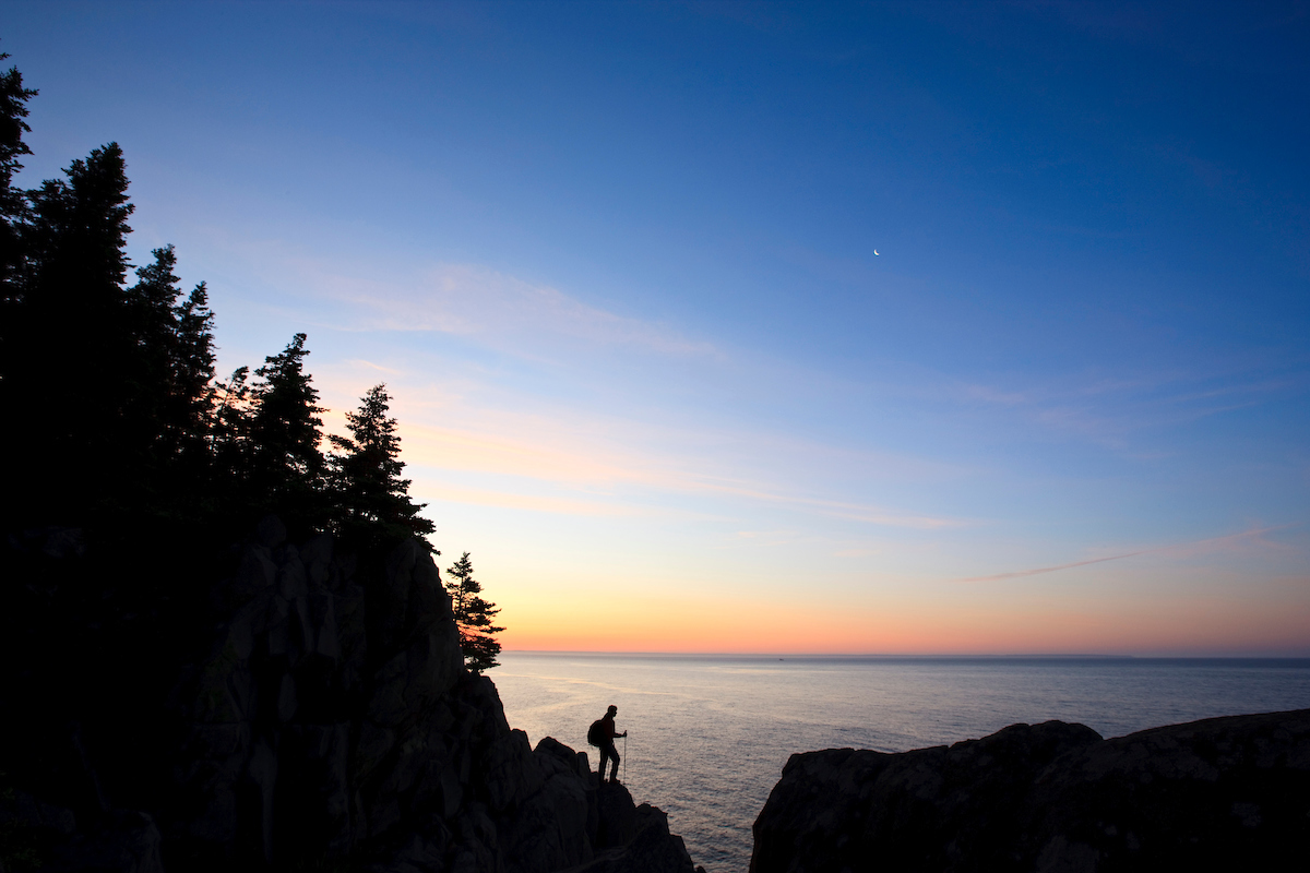 A lone hiker at sunrise on the Bold Coast trail in Cutler, Maine.