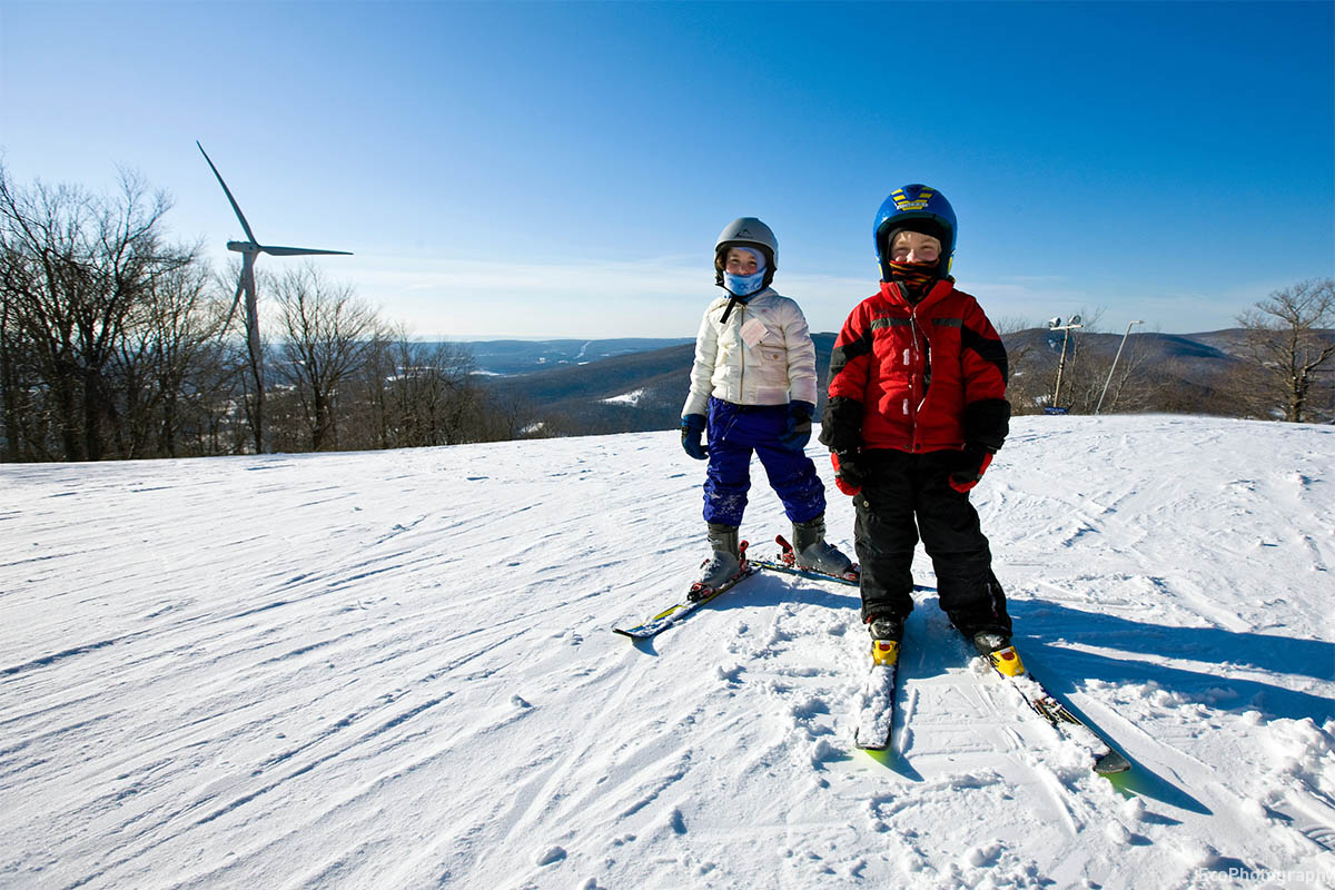 Kids skiing with wind turbine in the background