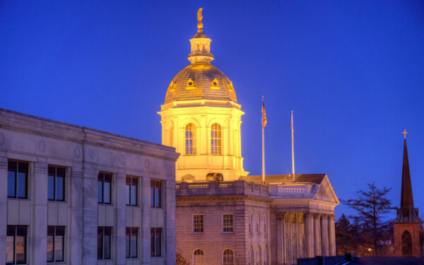 New Hampshire state house at night, with a spotlight on the dome.