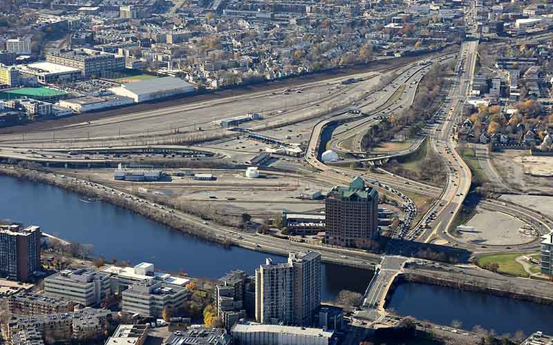 Aerial view of the Allston Interchange and surrounding rail yards, highways, and industrial land, showing the barriers dividing the neighborhood from the Charles River. The Allston Multimodal Project aims to reconnect these communities.